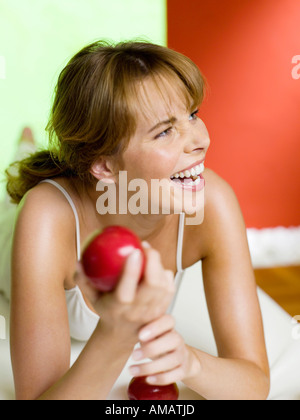 Frau auf Bett mit Apfel, lachen, Nahaufnahme Stockfoto