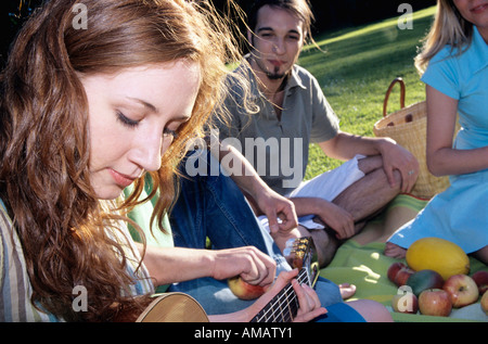 Junge Frau, die Gitarre für Freunde im Garten, Nahaufnahme Stockfoto