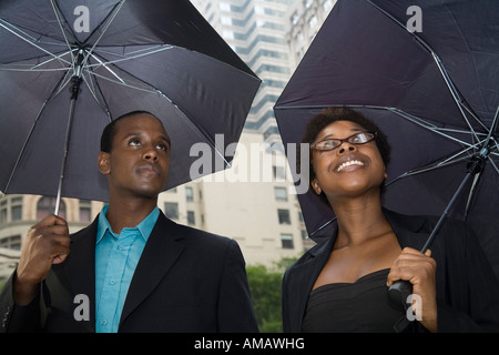 Mann und Frau Innenstadt, jeder stand unter einem Regenschirm Stockfoto