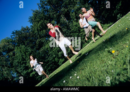 Vier junge Menschen, die durch den Garten laufen Stockfoto