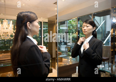 Eine Frau, die ihre Bluse im Spiegel einstellen Stockfoto