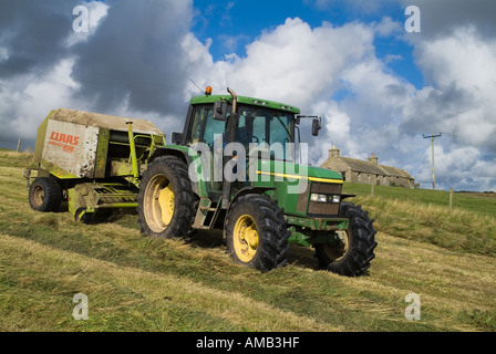 dh ERNTE UK Farm Traktor Ballenpresse trockene Silage Gras und Hütte Orhir Orkney Landwirt Maschine Feld Landmaschinen Walze Stockfoto