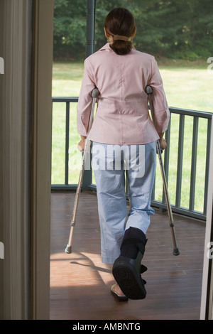 Rückansicht einer Frau gehen mit Krücken in einen Balkon Stockfoto