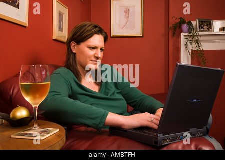 Frau arbeitet an einem Laptop und einem Glas Weißwein Stockfoto