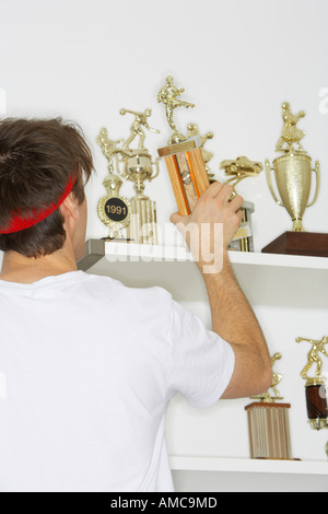 Mann Platzierung Trophäen auf Regal Stockfoto