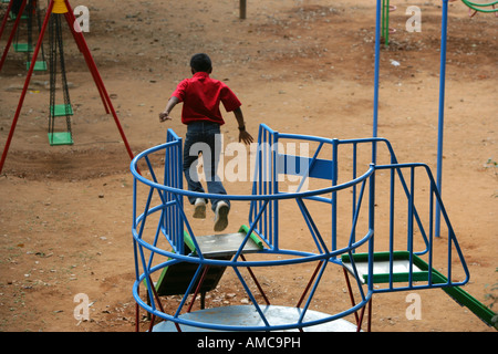 Mit einem Gefühl der Risikobereitschaft und Abenteuer springt ein kleiner Junge von einer Rutsche auf dem Spielplatz Stockfoto