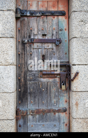 Solide Holztür mit alten Scharniere, Riegel und Vorhängeschloss in leichten Granitblöcke gesetzt Stockfoto