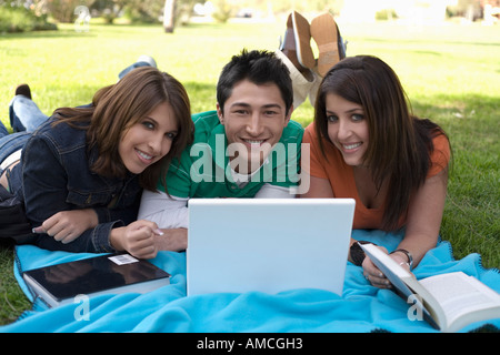 Junge Menschen liegen auf der Decke im Park mit Computer Stockfoto