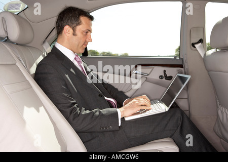 Geschäftsmann mit Laptop-Computer im Auto Stockfoto