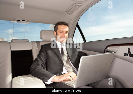 Geschäftsmann mit Laptop-Computer im Auto Stockfoto