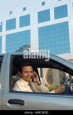 VEP72163 junge indische Executive mit Krawatte lächelnd und Gespräch am Mobiltelefon und Steuerwagen Stockfoto