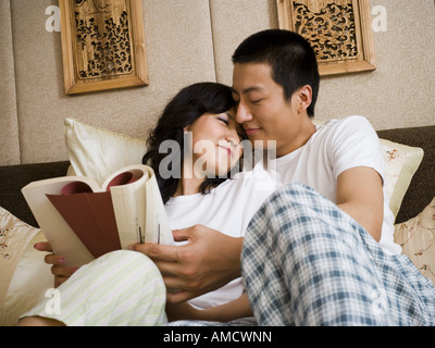 Paar im Bett kuscheln und lesen Stockfoto