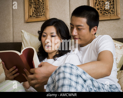 Paar im Bett kuscheln und lesen Stockfoto