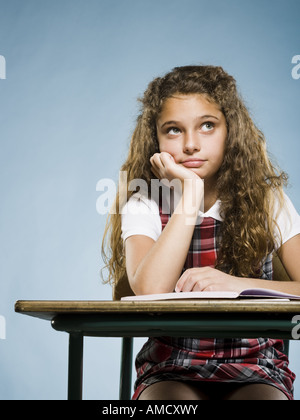 Mädchen mit Arbeitsmappe suchen am Schreibtisch sitzen gelangweilt Stockfoto