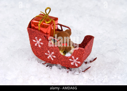 Urlaub-Schlitten ruht im Schnee mit ein Geschenk und ein Teddybär Stockfoto