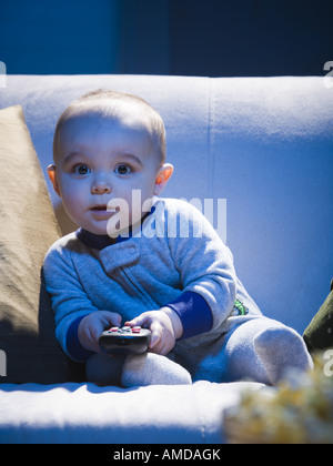 Baby auf Sofa mit TV-Fernbedienung Stockfoto