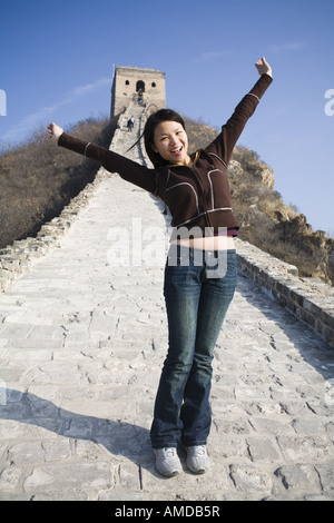 Mädchen mit Arme nach oben stehend auf Pfad an der chinesischen Mauer Stockfoto