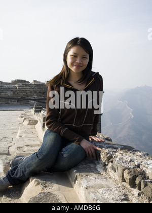 Mädchen sitzen auf Felsvorsprung auf der chinesischen Mauer Stockfoto