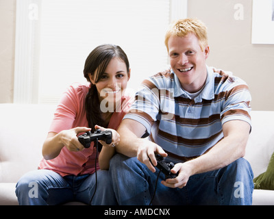 Mann und Frau auf Sofa spielen von Videospielen Stockfoto