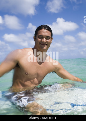 Mann sitzt auf Surfbrett im Wasser lächelnd Stockfoto