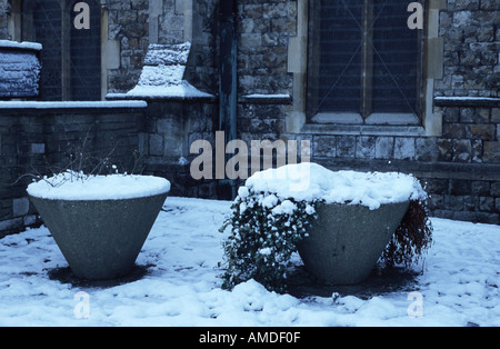 Blumentöpfe, verschneite St. Leonards Kirchhof Heston West London UK Stockfoto