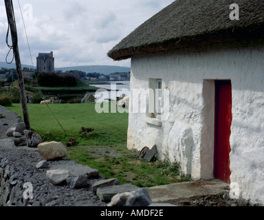 Weiß getünchte Stein strohgedeckten Hütte mit Dunghaire Schloss (oder Dongory Schloss) hinaus Kinvara, County Galway, Eire (Irland). Stockfoto