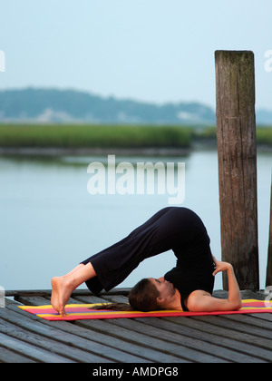 Frau tut Yogaposition Pflug am frühen Morgen auf Dock Virginia Beach, VA Stockfoto