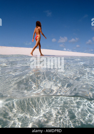 Turks Caicos Provo Grace Bay unter Frau im roten Badeanzug Spaziergänge Ozean s Rand spanische Münzen im Wasser Stockfoto