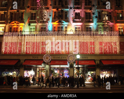 Hamleys Spielzeugladen Laden Markenlogo auf Fensterläden Winter Abenddämmerung beschäftigt mit Weihnachtseinkäufern in Regent Street West End Weihnachtsbeleuchtung Dekorationen London UK Stockfoto