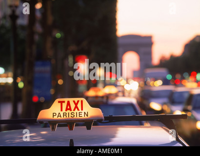 Taxis und Verkehr in der Abenddämmerung auf der Champs-Elysées mit dem Arc de Triomphe in Paris Stockfoto