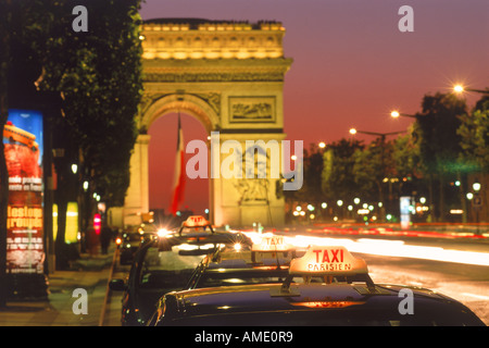 Taxis und Verkehr in der Nacht auf der Champs-Elysées mit dem Arc de Triomphe in Paris Stockfoto