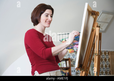 Seitenansicht einer lächelnden jungen Frau mit einem Pinsel malen. Stockfoto