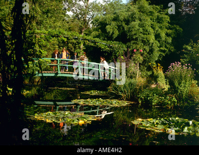 Touristen, die von üppiger Vegetation umgeben und stehen auf einem japanischen Holzbrücken überqueren den Seerosenteich in Claude Monet s Wassergärten gespeist wird der Fluss Epte in Giverny Stockfoto