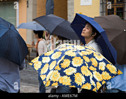 Orientalische Mann mit Wifi Hörer in Gruppe von Touristen mit Sonnenschirmen im Regen Rothenburg Ob der Tauber Deutschland Stockfoto