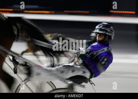 Nahaufnahme von Beschleunigung Trabrennen Jockey in der Nacht im Winter Ontario Stockfoto