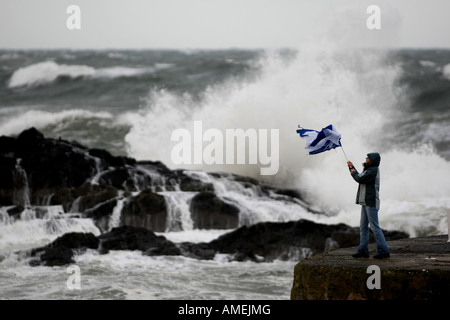 Frauen kämpfen mit Regenschirm bei Sturm an der Nordseeküste in Banff, Schottland, Vereinigtes Königreich Stockfoto