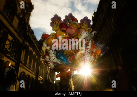Mann, Verkauf von einem großen Haufen Luftballons in einer Stadt Zentrum Straße Hintergrundbeleuchtung von der Sonne Stockfoto