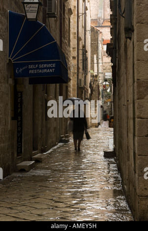 Eine ältere Dame mit Regenschirm Spaziergänge entlang einer schmalen Straße in der Altstadt von Dubrovnik, Kroatien (Motion Blur) Stockfoto