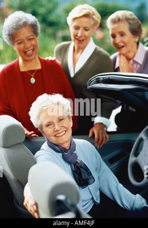 Drei Reife Frauen stehen in der Nähe von Reife Frau im Cabrio Stockfoto