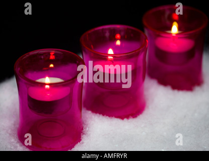 Kerzen in rosa Glas Teelichthalter Schuss stehend in faux Schnee mit schwarzem Hintergrund alit Stockfoto