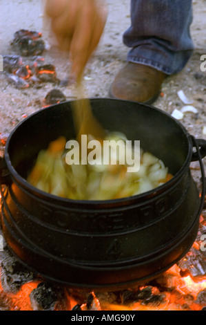 Kochen auf offenem Feuer einen kleinen Kessel auf eine Outdoor-Holz-Feuer-Hand rühren die Brühe Stockfoto