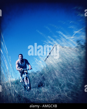 Mann, Radfahren durch Feld hohes Grass, Maine, USA Stockfoto