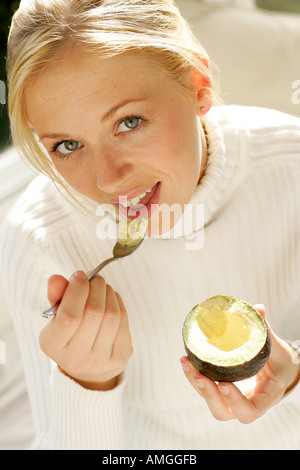 Lässige Porträt blonde Mädchen essen avocado Stockfoto