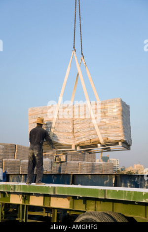 Import von Baumaterialien, Handwerker Paletten Entladen der iranischen Zement, per Schiff am Kai von Al Sharjah, Dubai, UAE geliefert Stockfoto