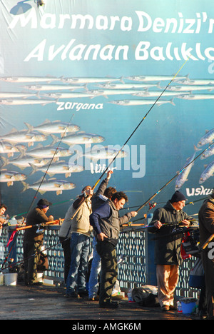 ISTANBUL-Linie Angeln in das Goldene Horn von der Galata-Brücke, mit riesigen Fisch Plakat hinter. 2007. Stockfoto