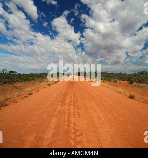 Red Australian Rural Road mit bewölktem blauen Himmel, NSW Outback, Australien Stockfoto