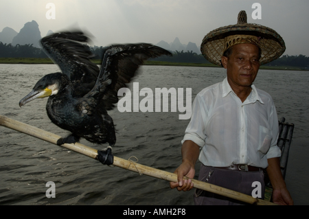 Porträt eines Fischers, hält ein Mast mit einem Kormoran ausgewogen am Ende, Li-Fluss, Yangshuo, Guangxi, China. Stockfoto