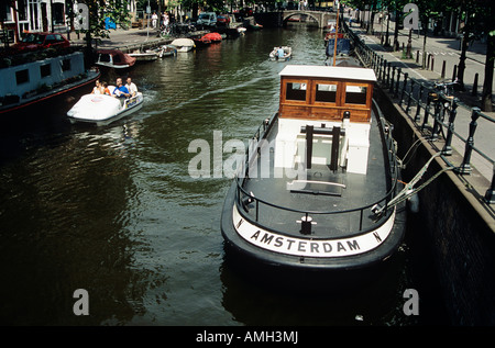 Boot vor Anker an einem Kanal neben einer Straße, Touristen im Tretboot, Amsterdam, Holland Stockfoto