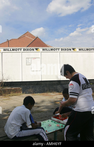 Jungs spielen das Brettspiel Monopoly auf einem alten Spielplatz auf einer Wohnsiedlung, regeneriert werden. Stockfoto