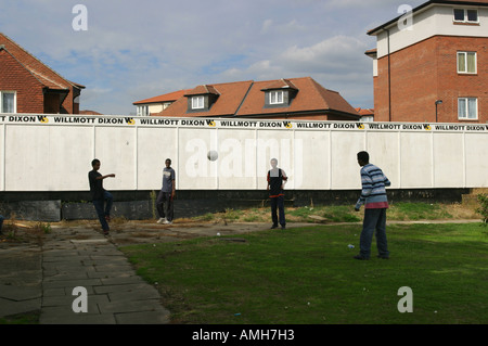 Jungen spielen Fußball auf einem stillgelegten Spielplatz auf einer Wohnsiedlung, regeneriert werden. Hintergrund: Dach des neuen Gehäuses. Stockfoto